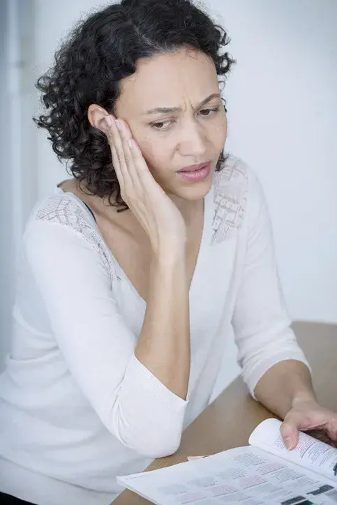 Frau hält sich die Hand an das Ohr